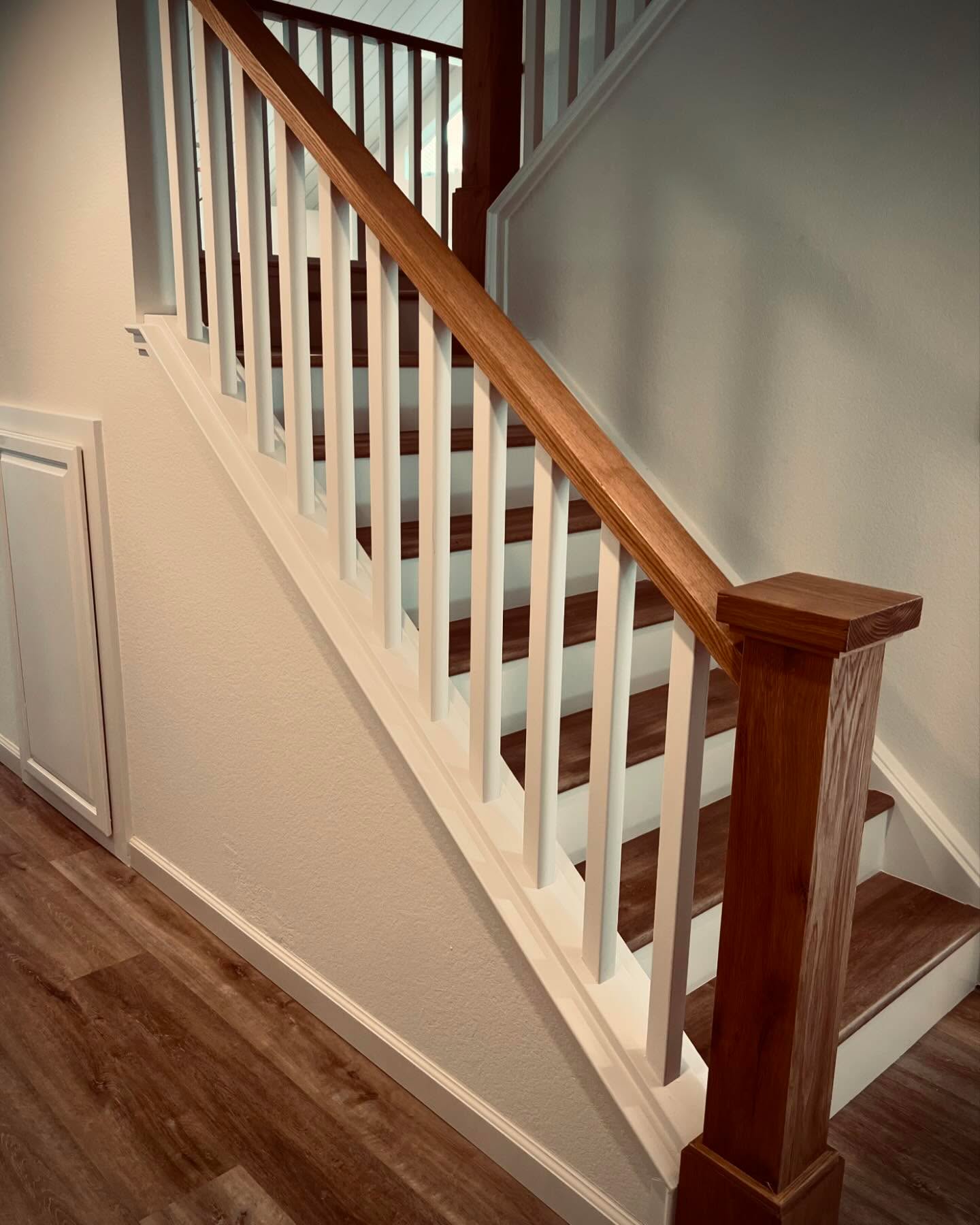 Staircase with white balusters and wood rail — Niche Construction