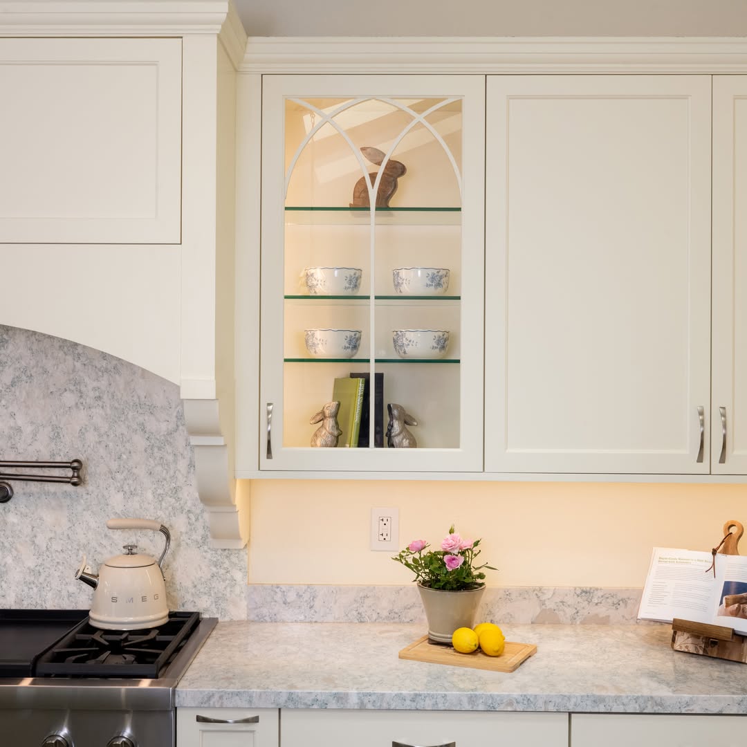 White kitchen with lit glass-front upper cabinets — Niche Construction
