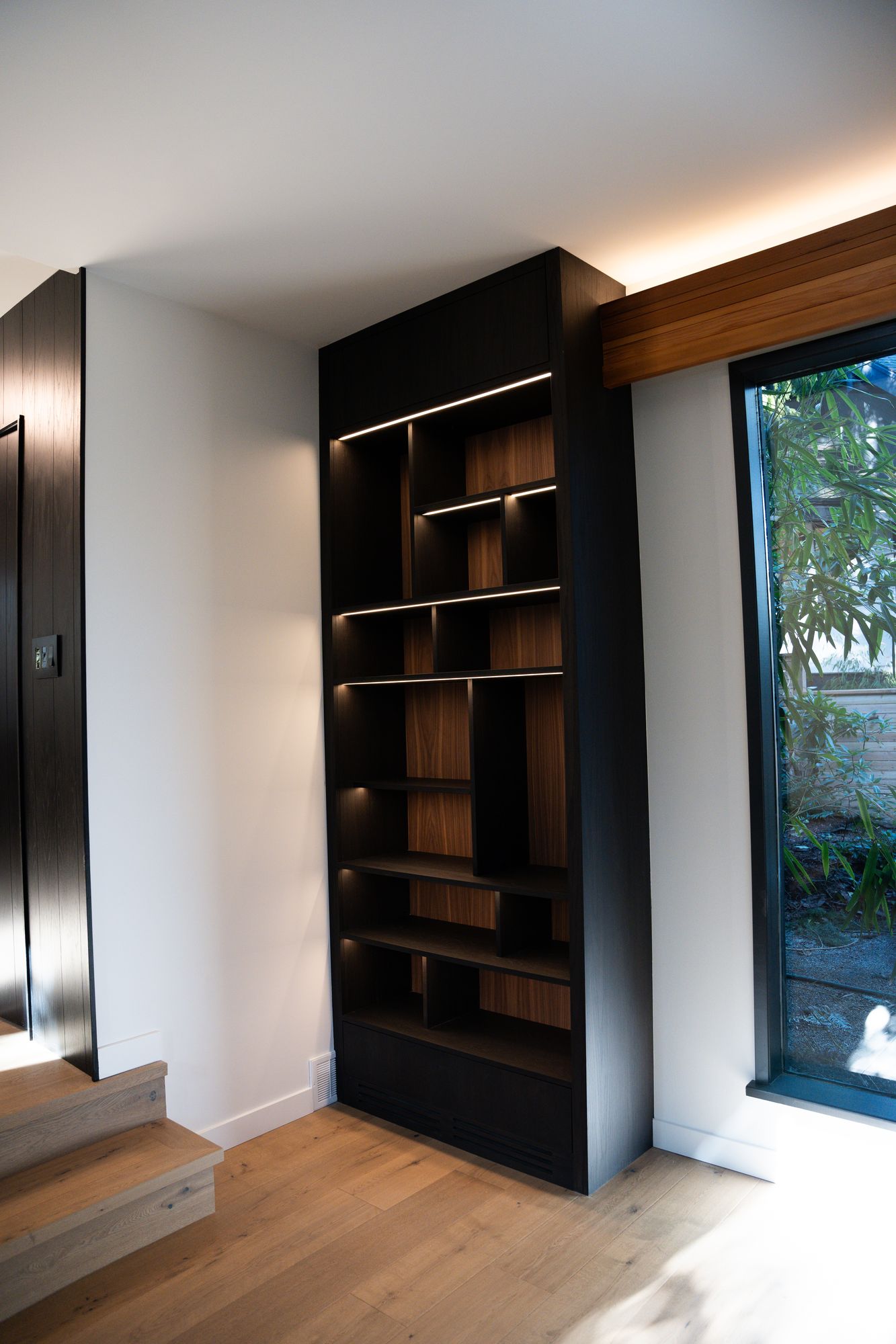 Custom black built-in shelving with wood beam detail and hardwood floors