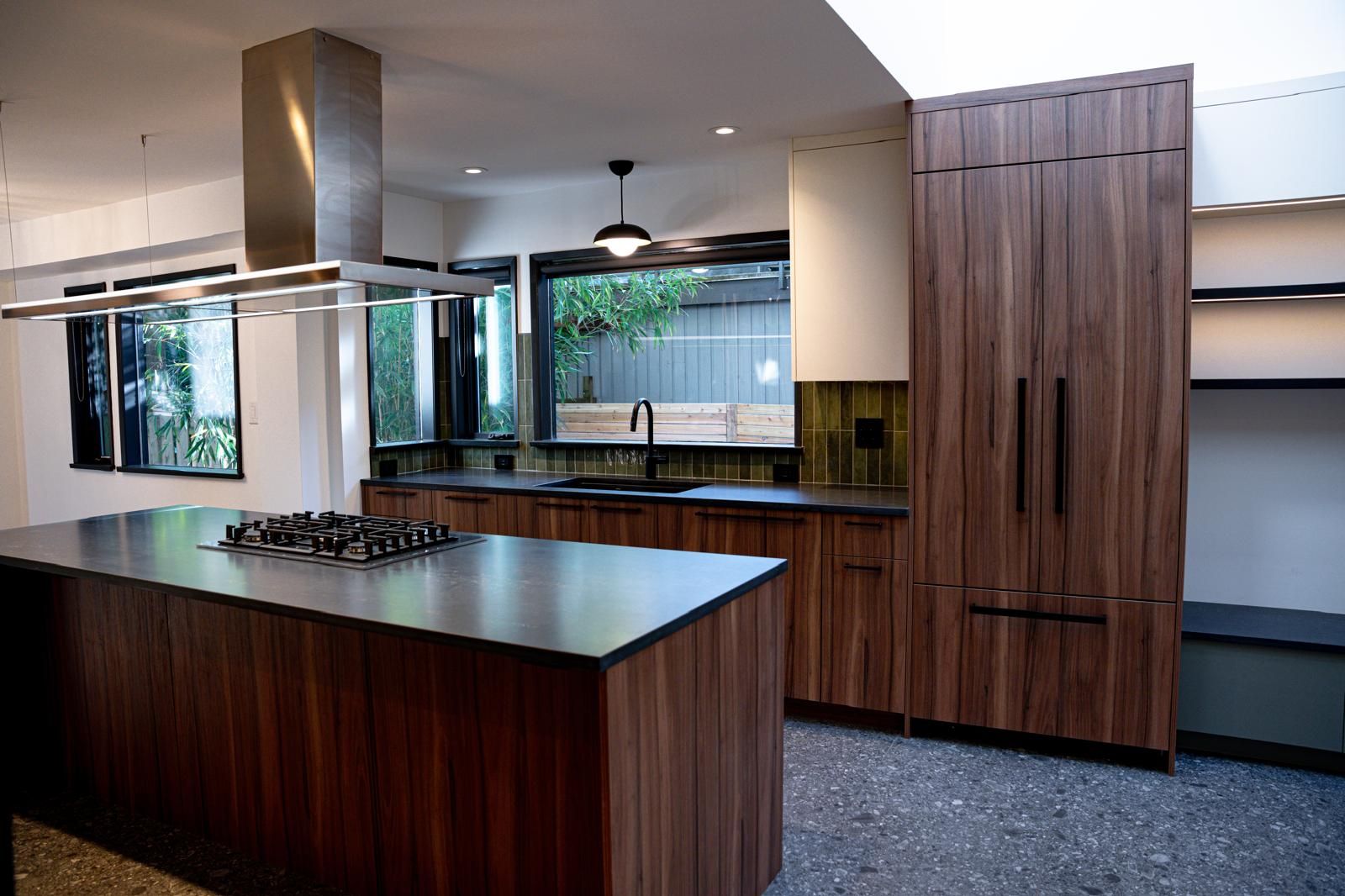 Renovated kitchen with walnut island, gas cooktop, stainless range hood and floor-to-ceiling walnut cabinetry