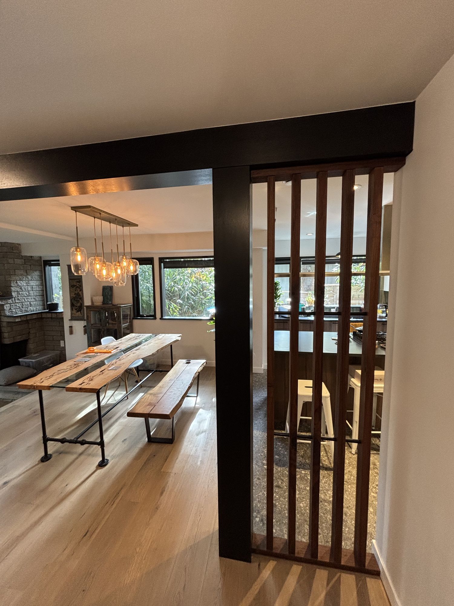 Dining area with black wood slat divider, wood dining table and bench