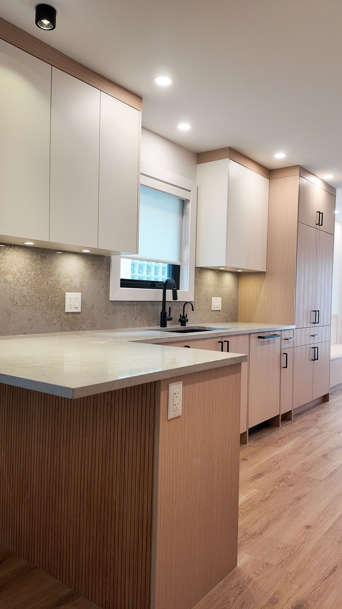 Kitchen renovation with light wood cabinets, quartz counters and under-cabinet lighting