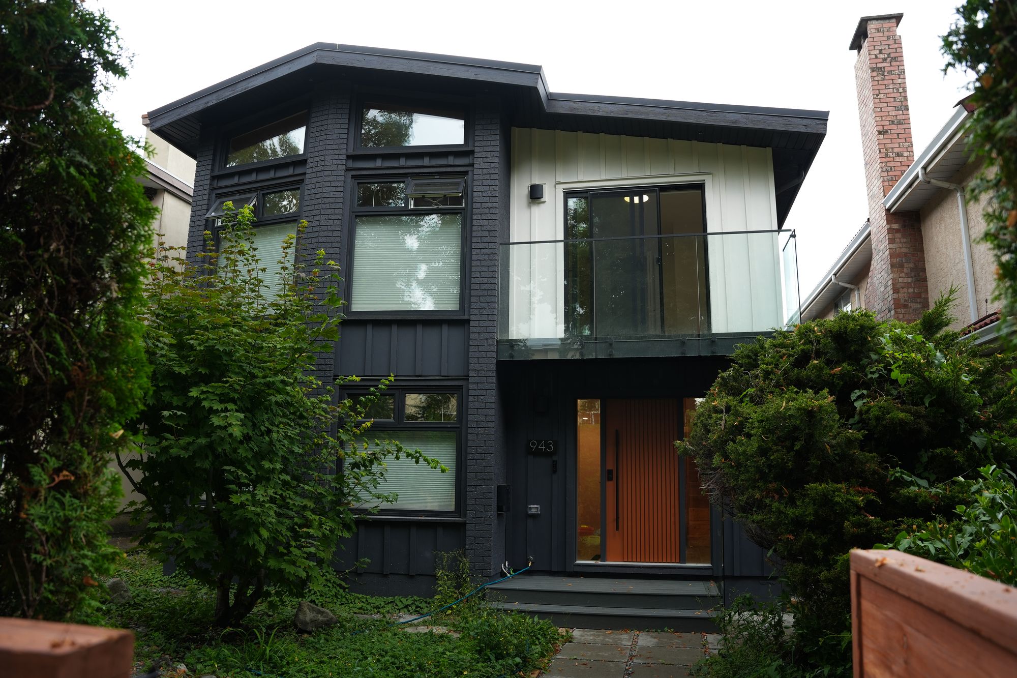 Renovated two-storey home exterior with dark siding and wood front door