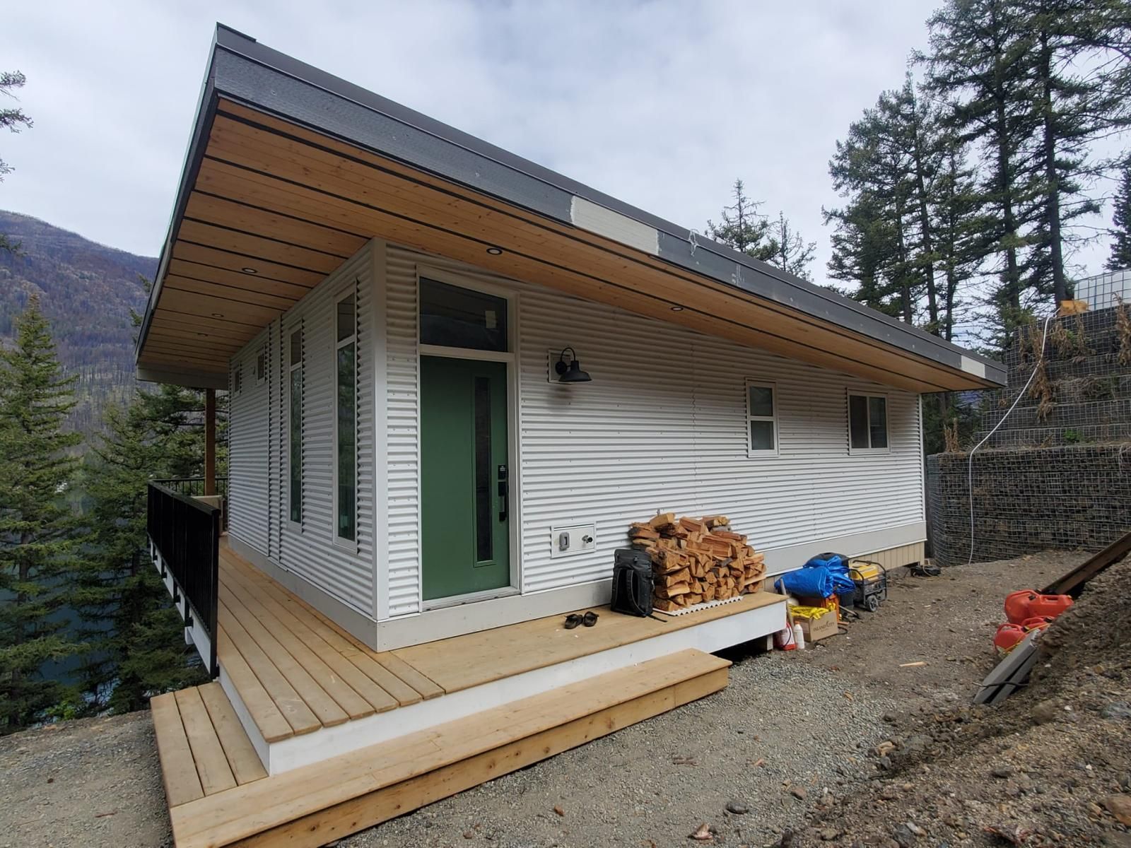 Custom mountain cabin with white siding, wood soffit roof overhang and cedar deck