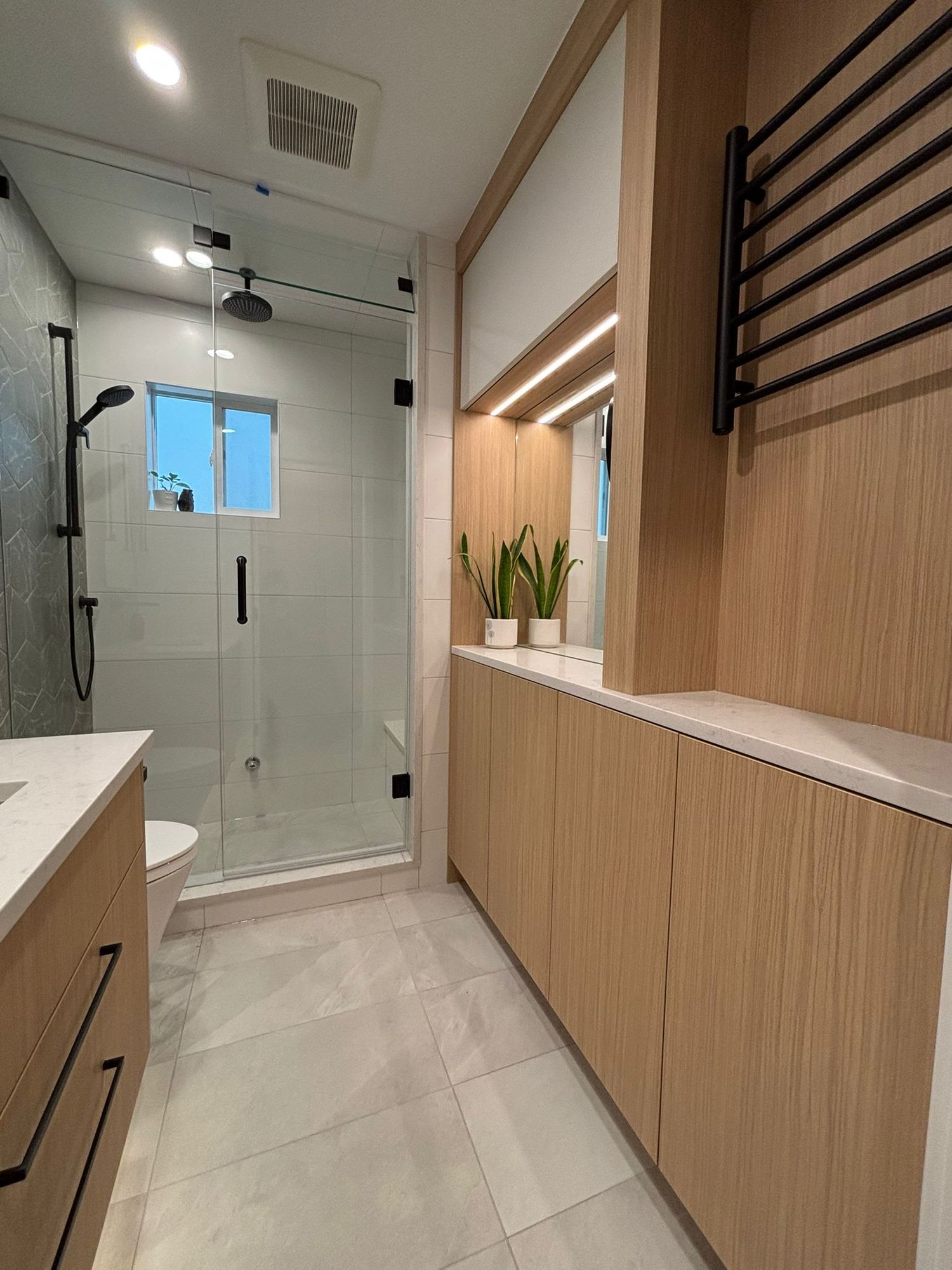 Bathroom renovation with glass shower, wood vanity and black heated towel rail