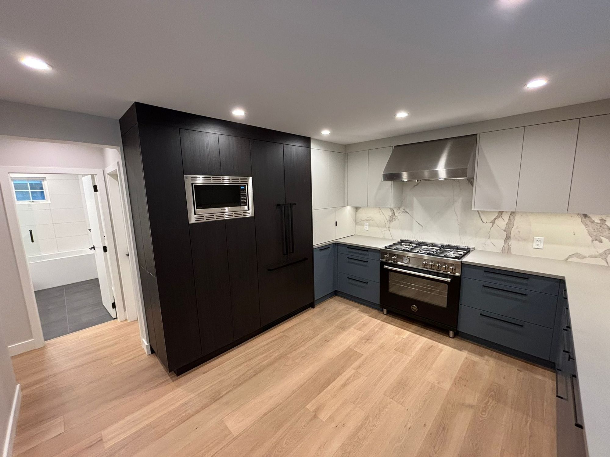 Kitchen renovation with black built-in oven wall, stainless range and marble backsplash