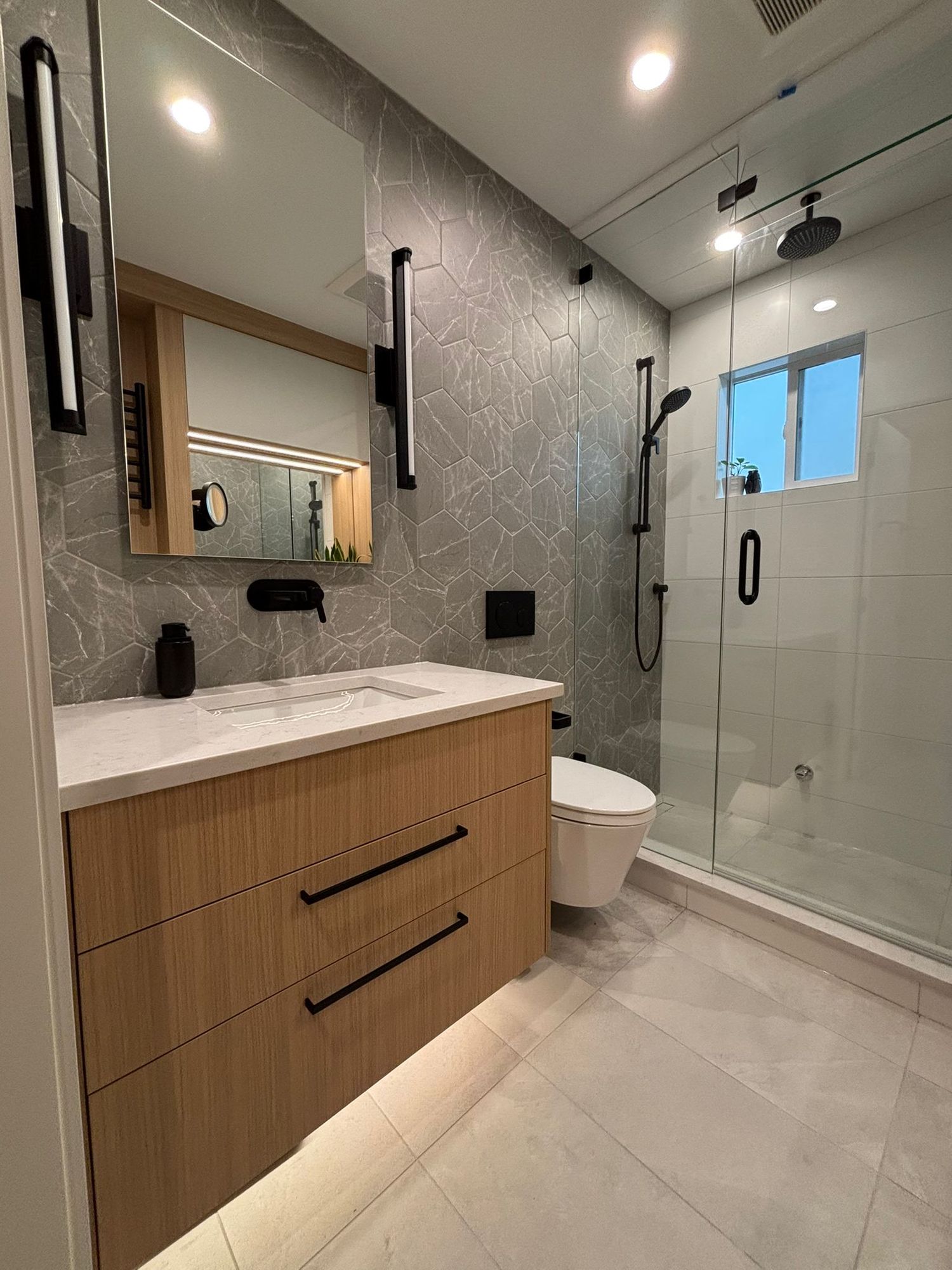 Bathroom renovation with floating wood vanity, glass shower and matte black fixtures
