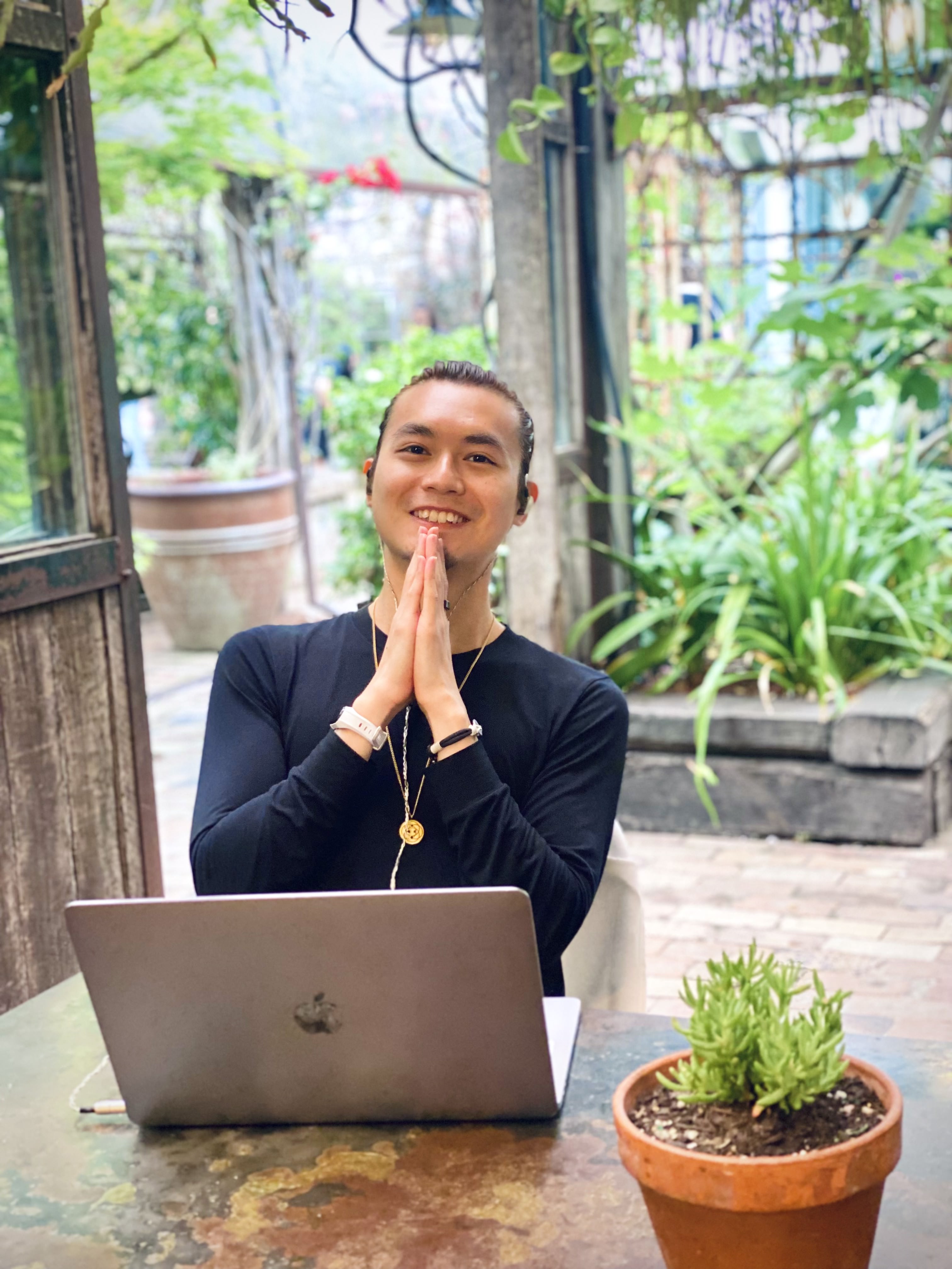 Freeman Fung, sitting, laptop in front, praying hands