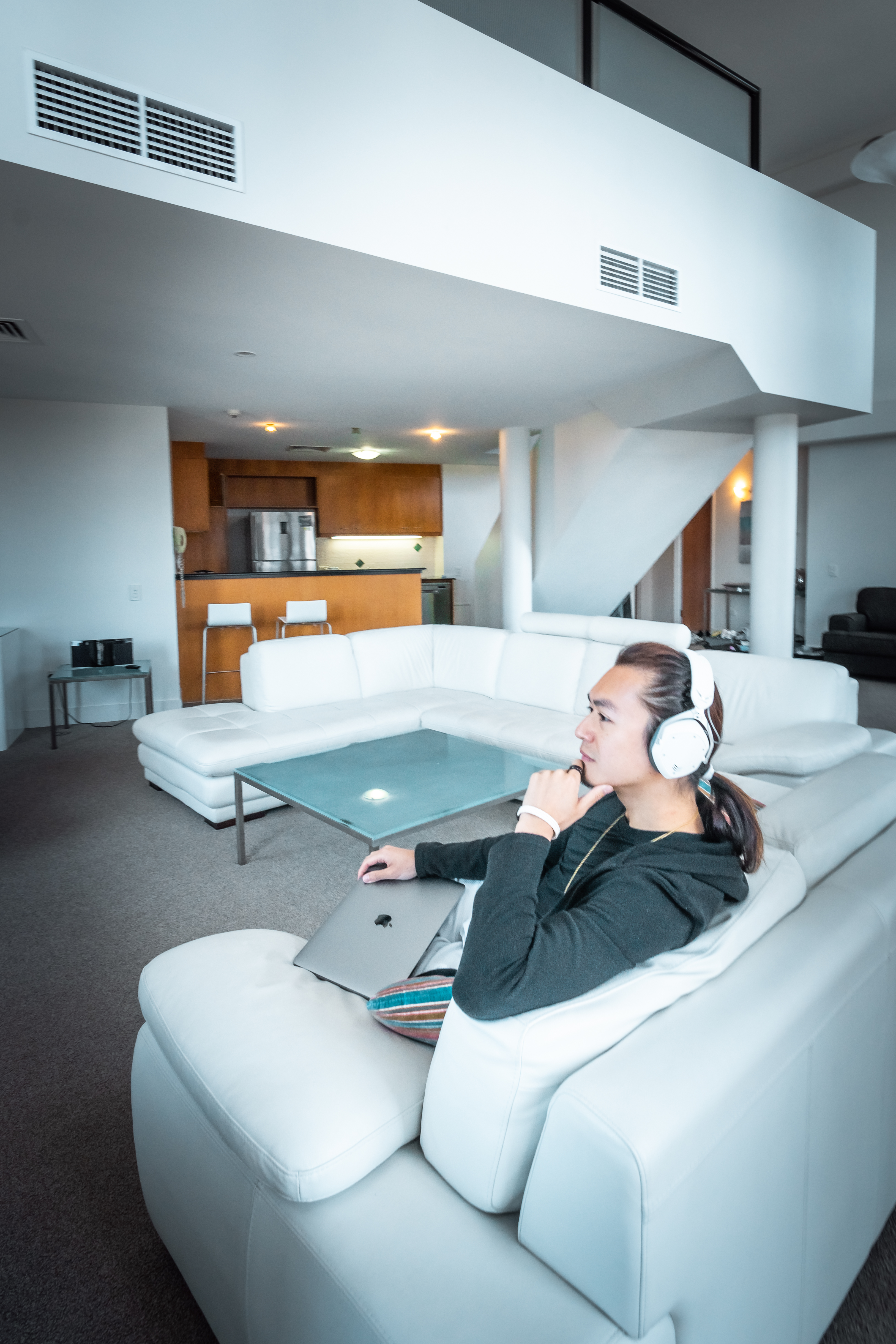 Freeman Fung sitting on a white couch with headphone and laptop
