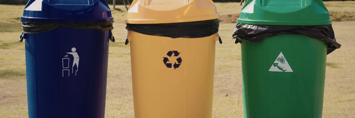 Three recycling bins for waste sorting in outdoor area.