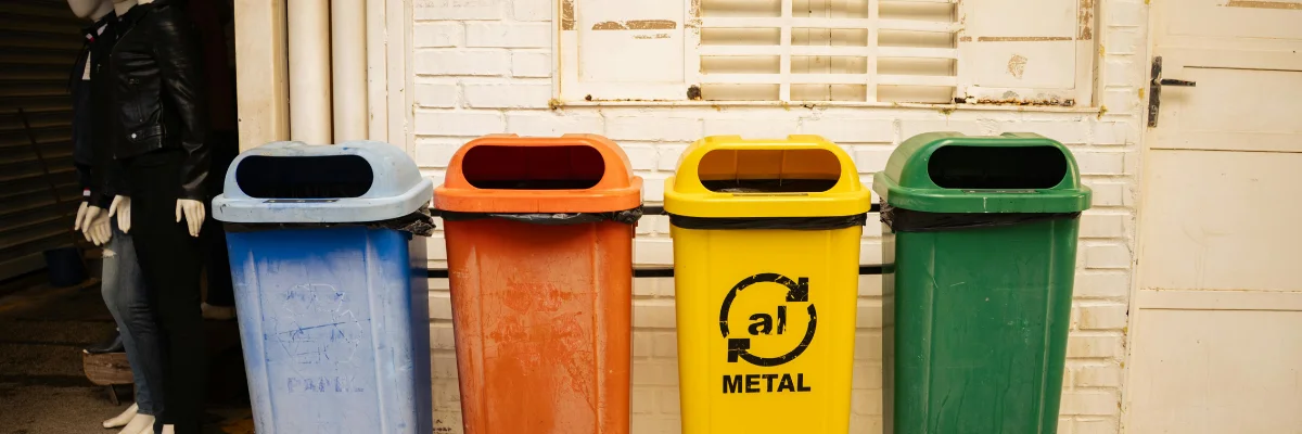 Row of blue, orange, yellow, and green recycling bins outside building.