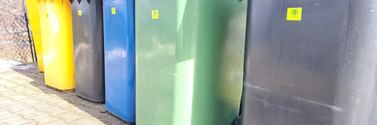 Row of large colorful recycling bins lined along sidewalk.
