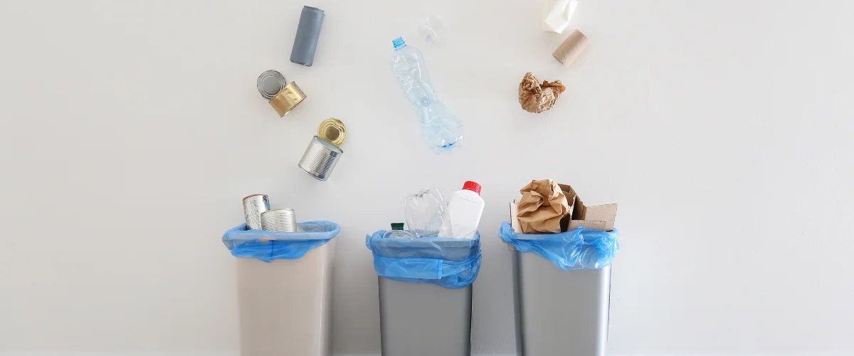 Recyclable items falling into three waste sorting bins. Recyclable items falling into three waste sorting bins.