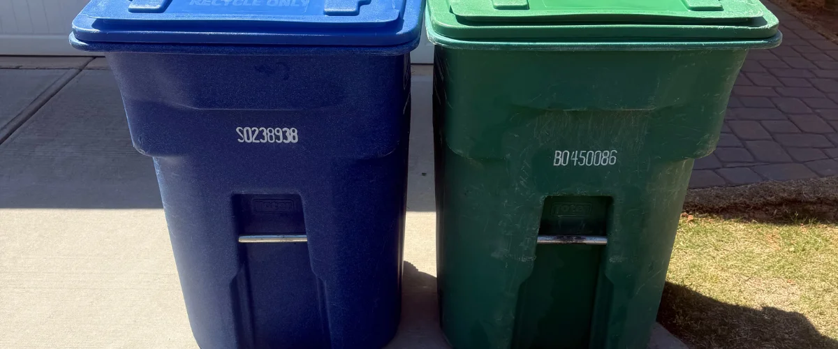 A bright blue recycling bin and a dark green trash bin stand side-by-side on a sunny day. A bright blue recycling bin and a dark green trash bin stand side-by-side on a sunny day.