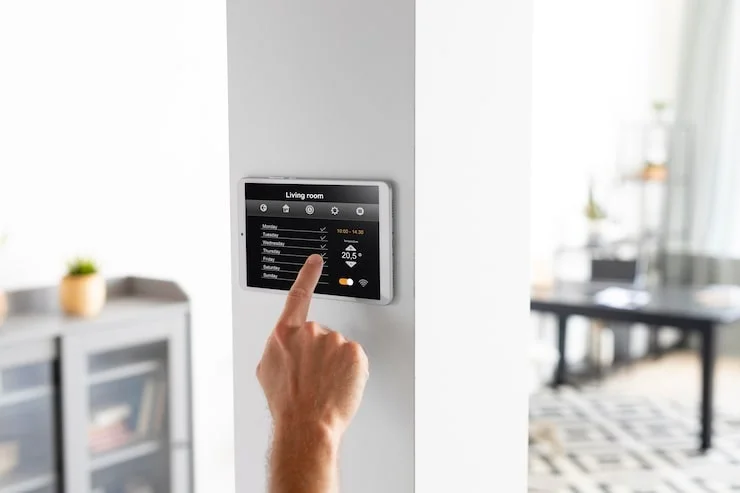 A male hand interacts with a wall-mounted tablet displaying smart home controls for living room settings.
