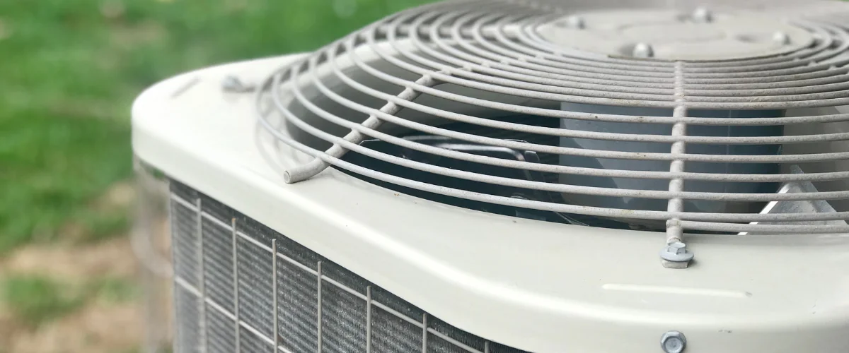 A close-up, slightly high-angle view of the white top and fan grille of an outdoor air conditioner unit.