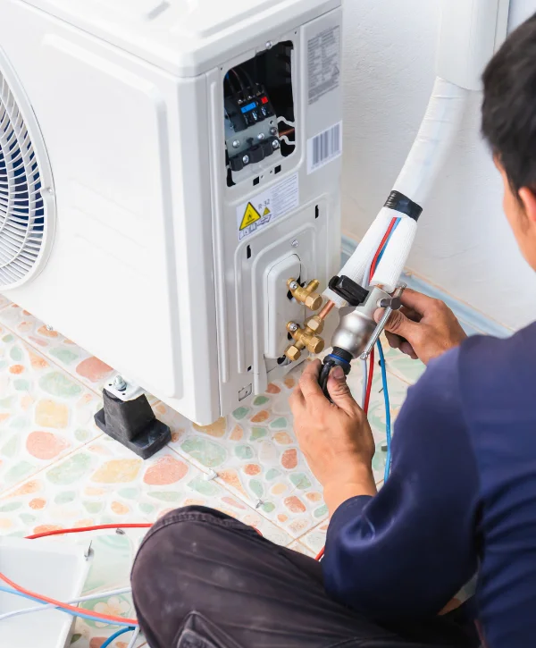 Close-up of a technician's hands using wrenches to install an outdoor air conditioning unit with wires and insulation.