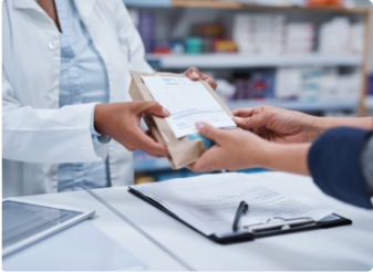 Pharmacist handing a paper prescription bag across the counter to a customer