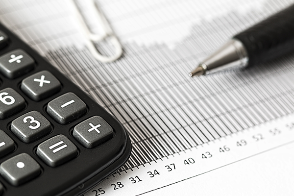 Calculator and pen resting on a printed accounting ledger
