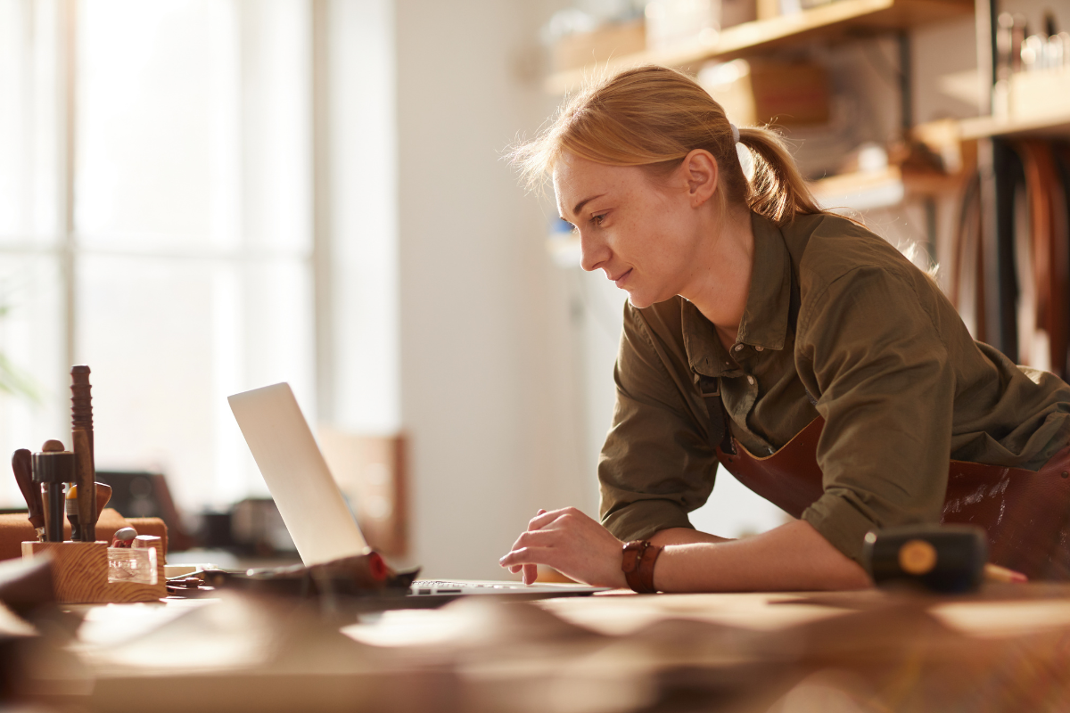 Creative business owner in her workshop looking at her laptop Creative business owner in her workshop looking at her laptop