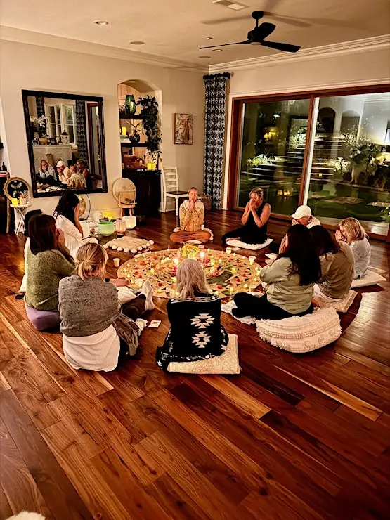 Women in a candlelit circle around a floral mandala