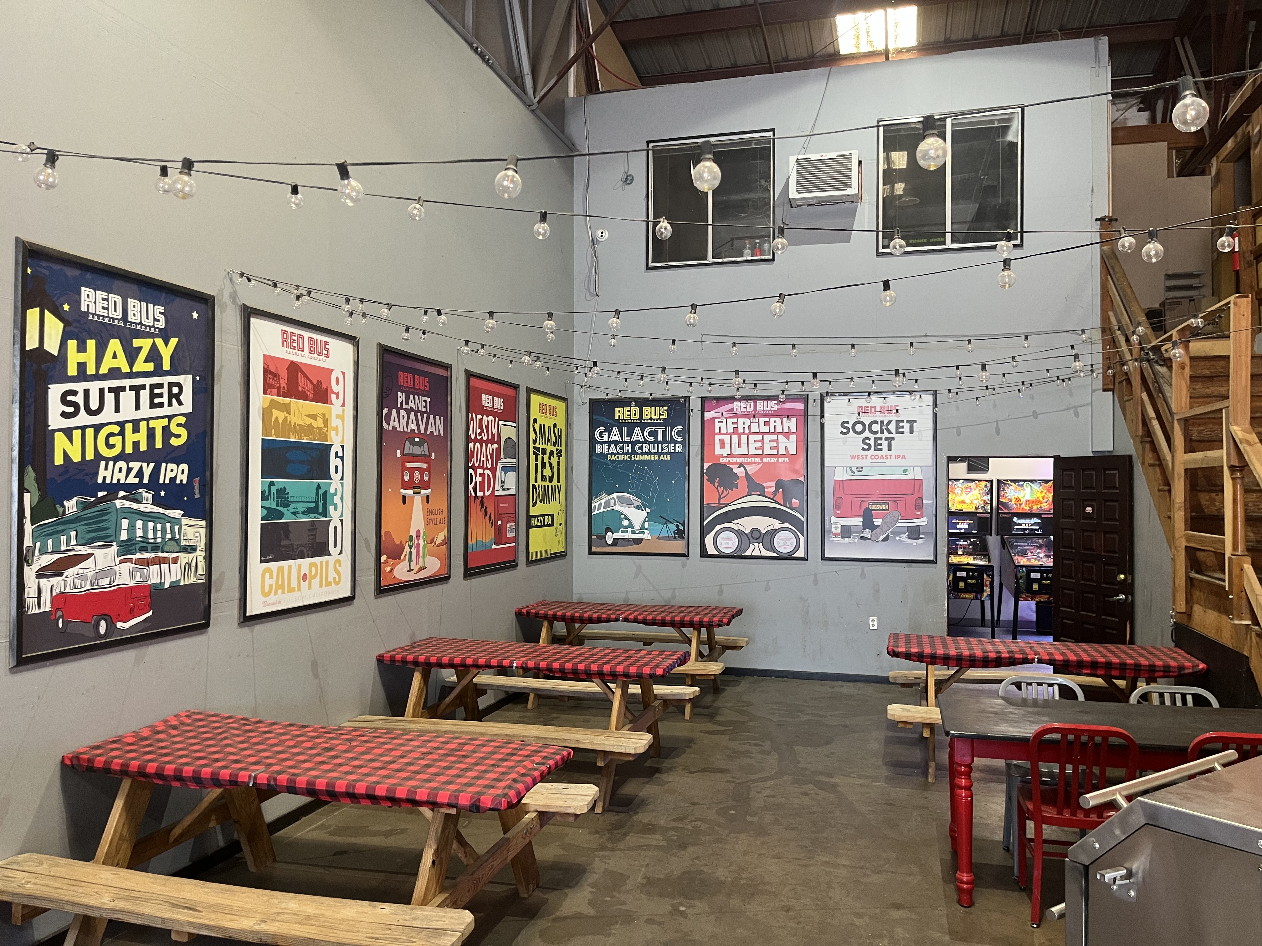 Red Bus beer posters and string lights over picnic tables inside the brewery