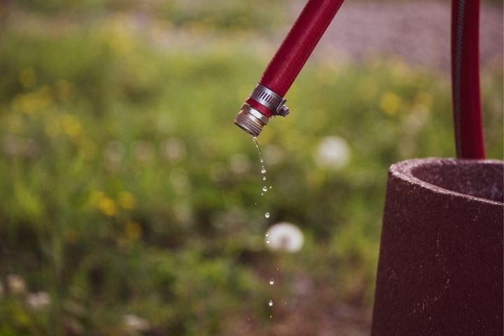 A dripping red hose explaining why is my water bill so high.