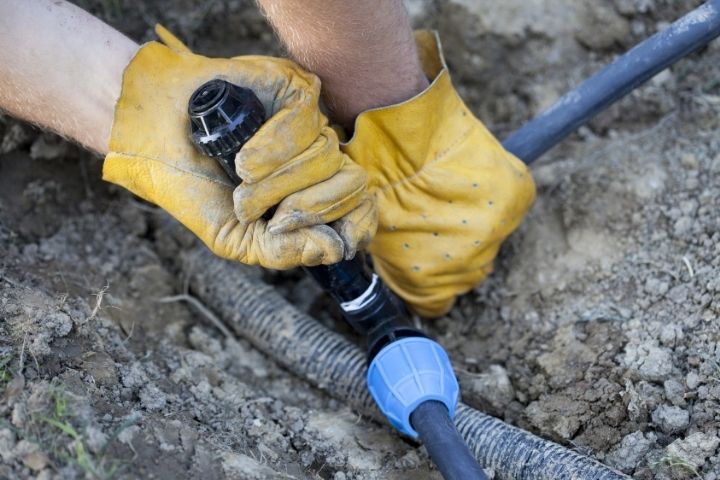 A plumber checking an irrigation setup to inspect for outdoor plumbing issues.
