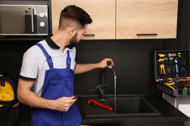 A plumber examining a faucet to provide preventative plumbing service near me.