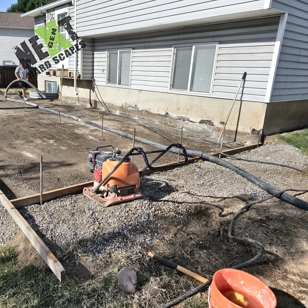 Compacted gravel base is prepared and timber framing is installed for the concrete patio adjacent to the house.