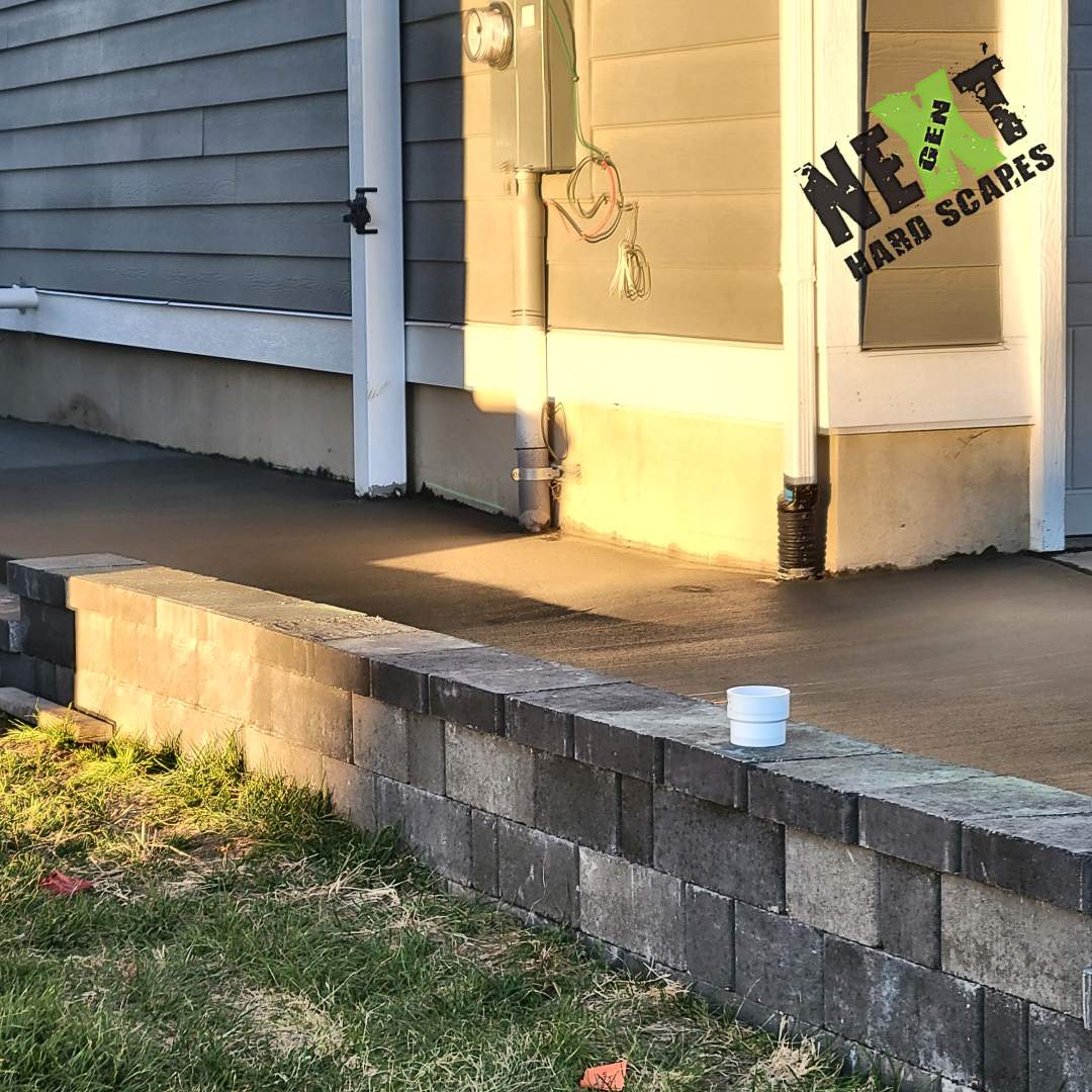 Close-up of the juncture between the retaining wall and the home's foundation, with smooth, clean concrete connecting the elements.