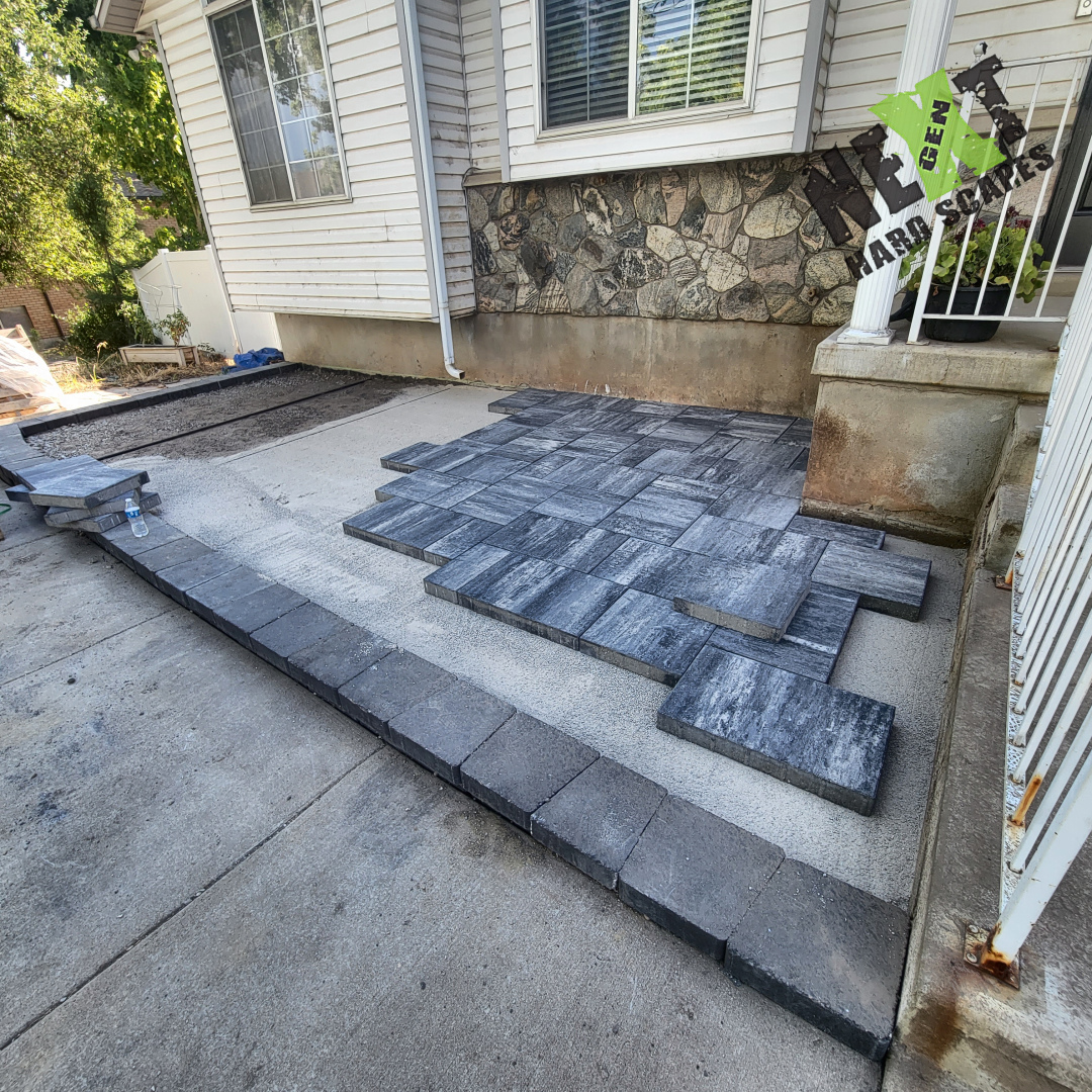 Laying out the first section of the porch pavers on a well-prepared base with clean, straight edging blocks in place. Laying out the first section of the porch pavers on a well-prepared base with clean, straight edging blocks in place.