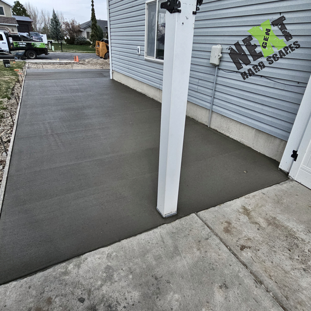 Freshly poured concrete extends from the garage opening with smooth, uniform finishing, and clean edges defined by solid formwork.