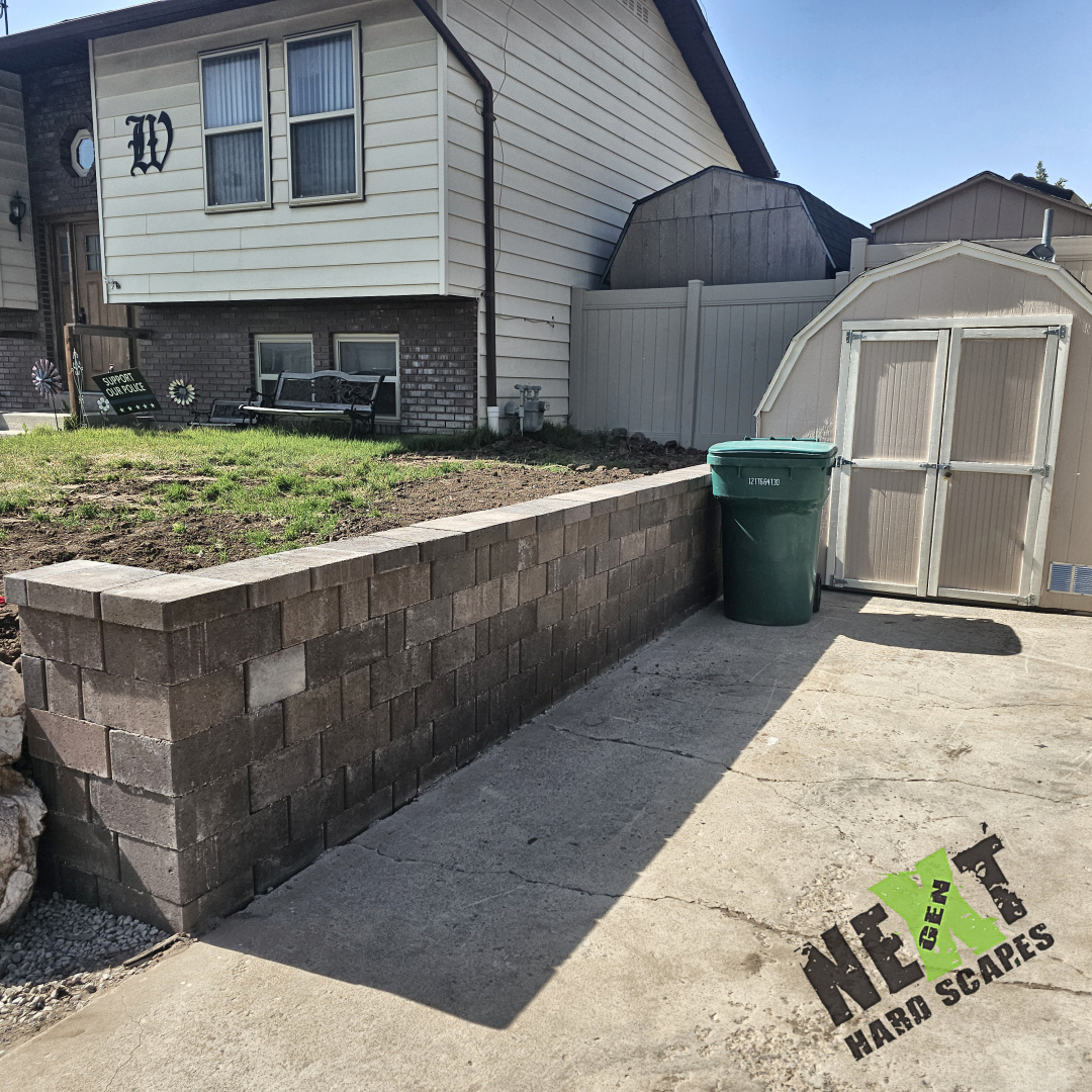 The new brick retaining wall fully laid with a straight, clean top row, demonstrating tight joints and uniform brick alignment.