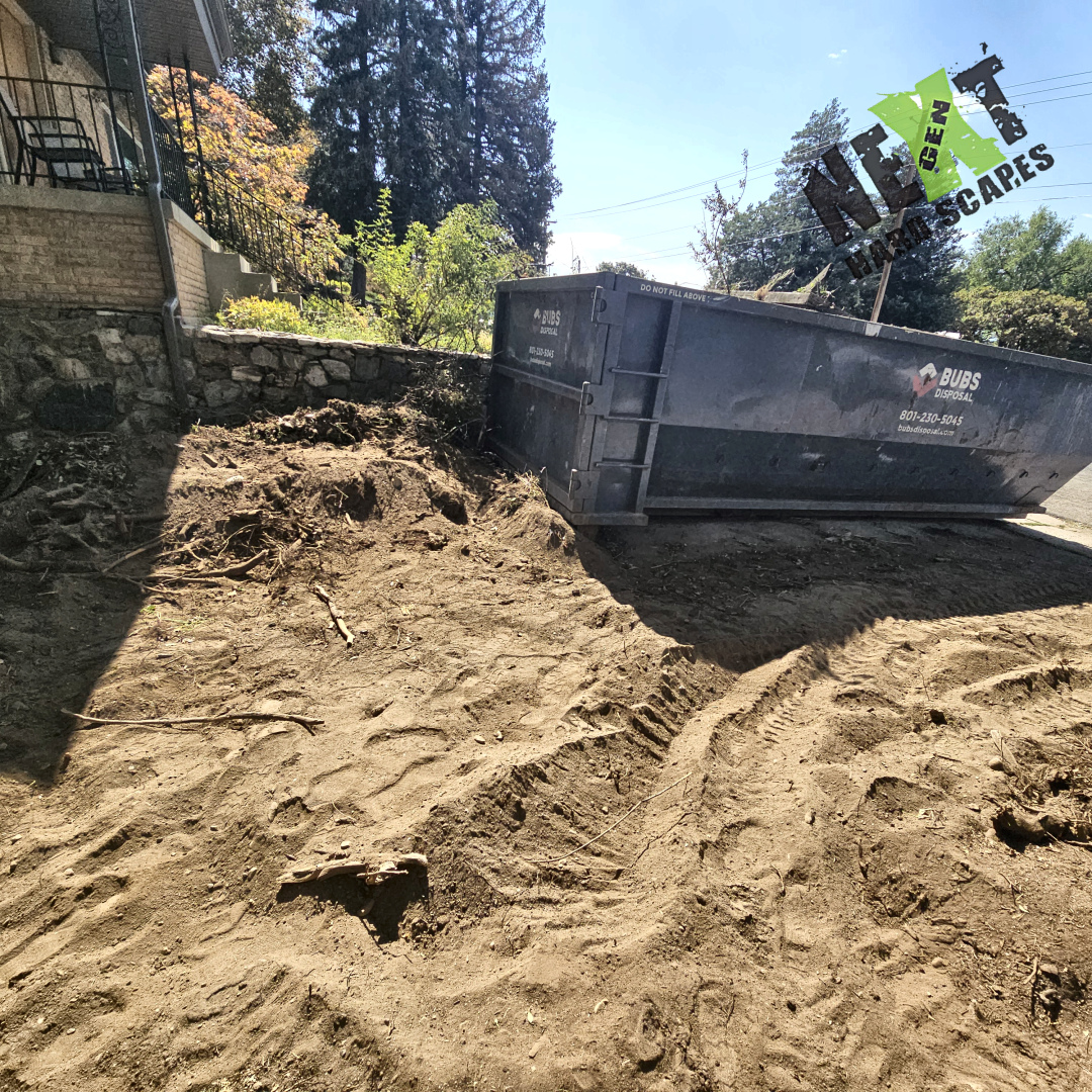 The clearing of the driveway and excess dirt around the retaining wall.
