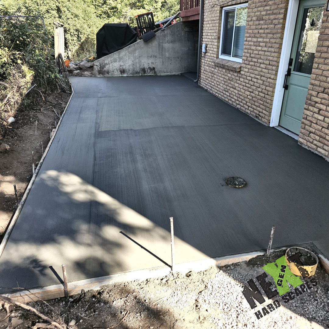 Fresh concrete pour on the side porch shows clean edges and a finely smoothed surface ready to cure.
