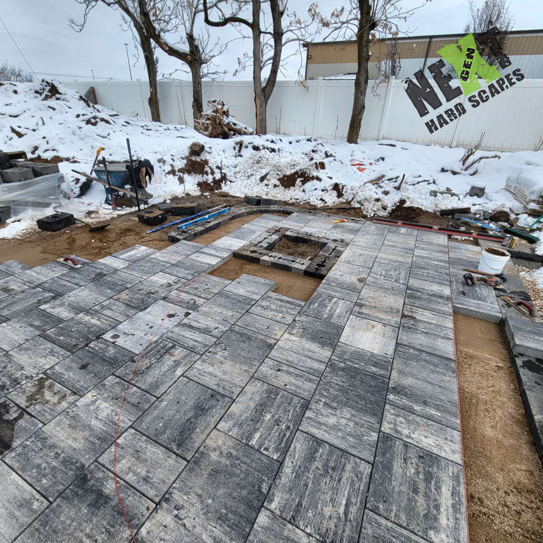 Layout of pavers for the patio underway with careful fitting around a square opening, maintaining consistent joint widths. Layout of pavers for the patio underway with careful fitting around a square opening, maintaining consistent joint widths.