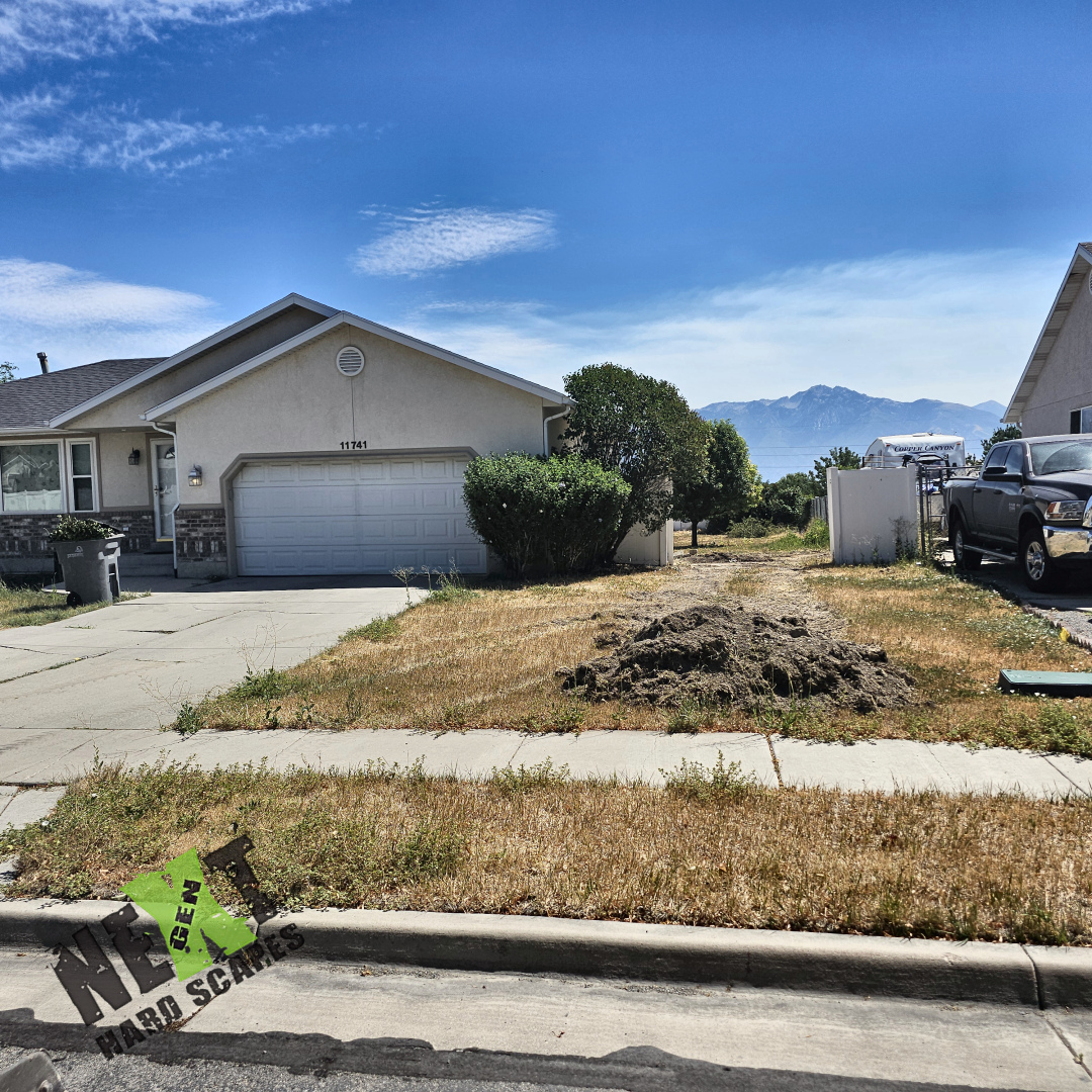 View of the existing front driveway and the adjacent side yard with grass and a noticeable pile of dirt before any demolition. View of the existing front driveway and the adjacent side yard with grass and a noticeable pile of dirt before any demolition.