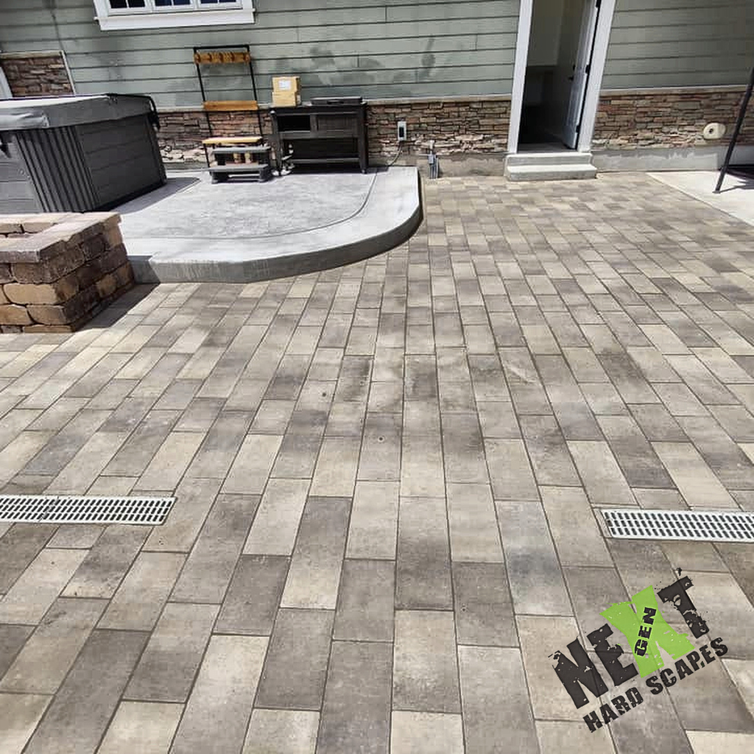 Concrete pad laid for the hot tub with smooth rounded edges and adjacent paver installation visible. Concrete pad laid for the hot tub with smooth rounded edges and adjacent paver installation visible.