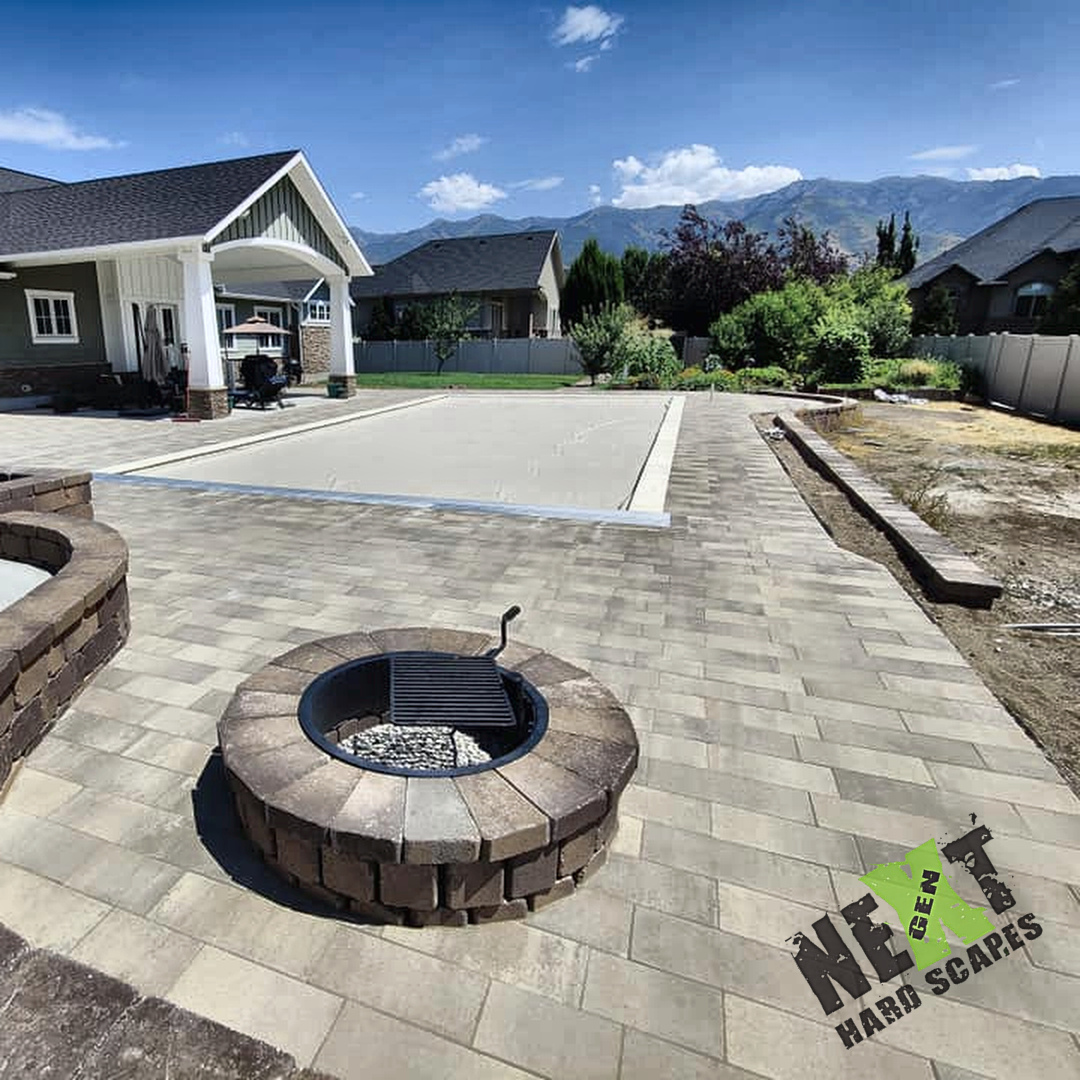 Finished paver surface around the covered patio, pool, and fire pit showing clean layout and integrated drainage components. Finished paver surface around the covered patio, pool, and fire pit showing clean layout and integrated drainage components.