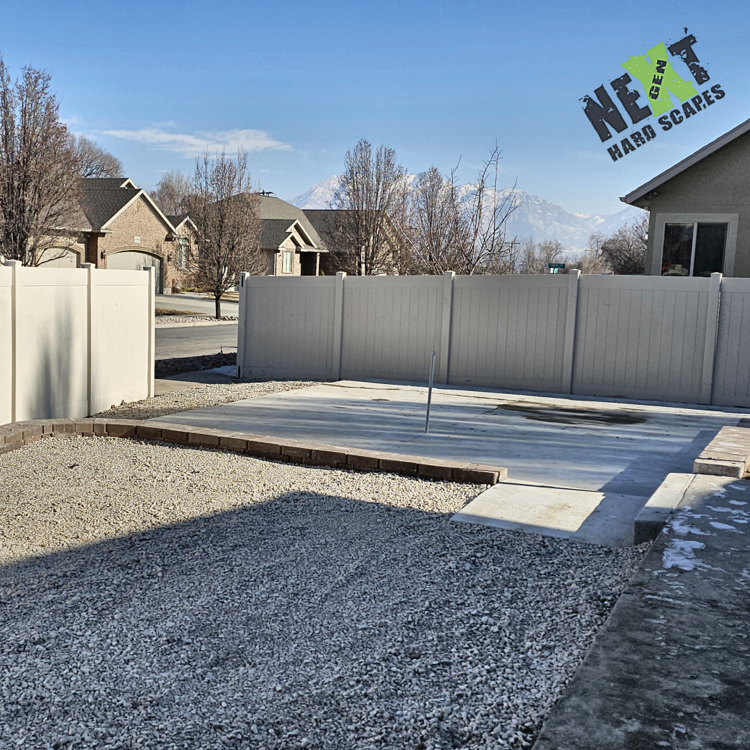 Overall view from the gate showing the poured slab, surrounding compacted gravel inside the retaining walls, and the conduit positioned for the future pergola. Overall view from the gate showing the poured slab, surrounding compacted gravel inside the retaining walls, and the conduit positioned for the future pergola.