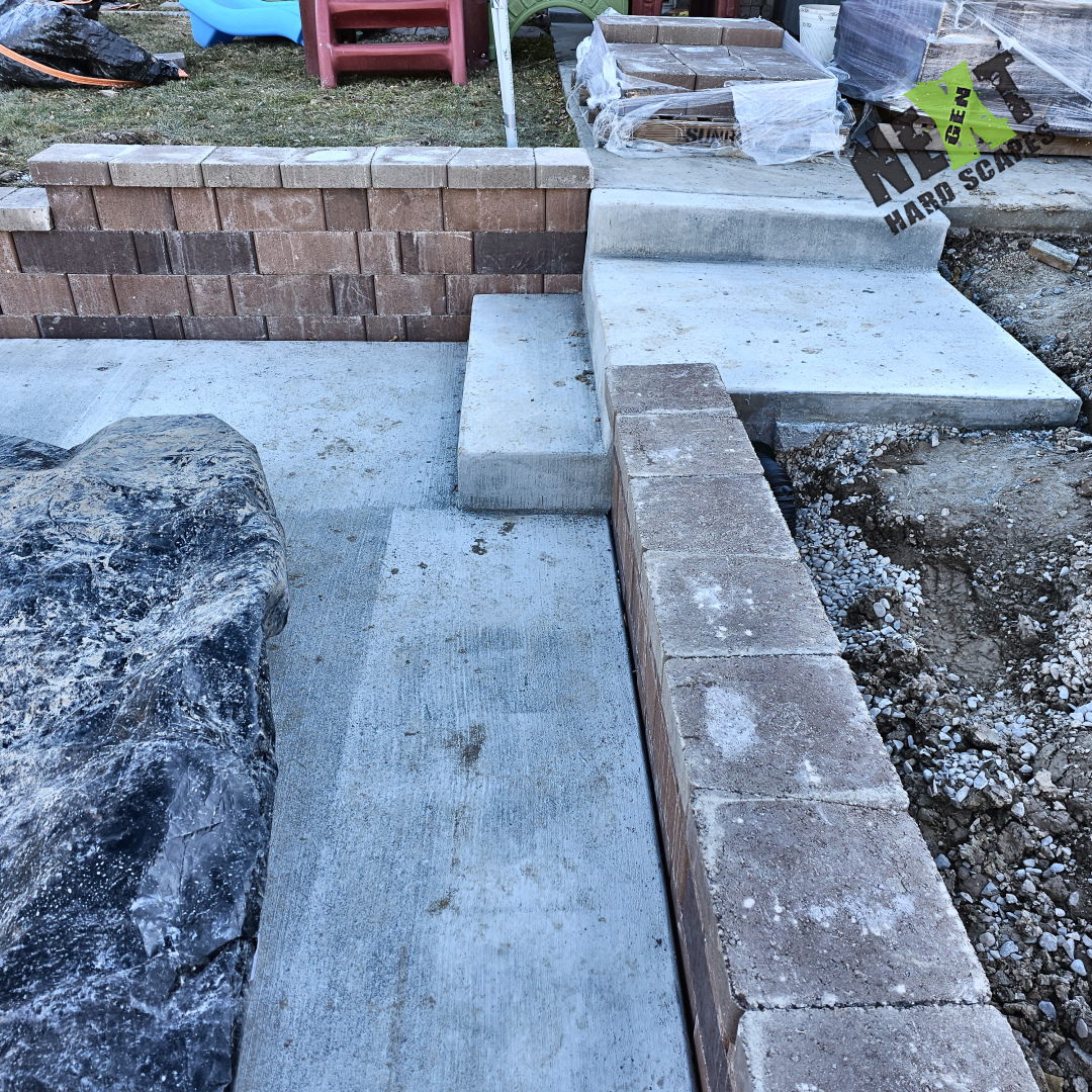 Wall corner and capstones set in place, showing tight joint alignment with concrete steps. Wall corner and capstones set in place, showing tight joint alignment with concrete steps.