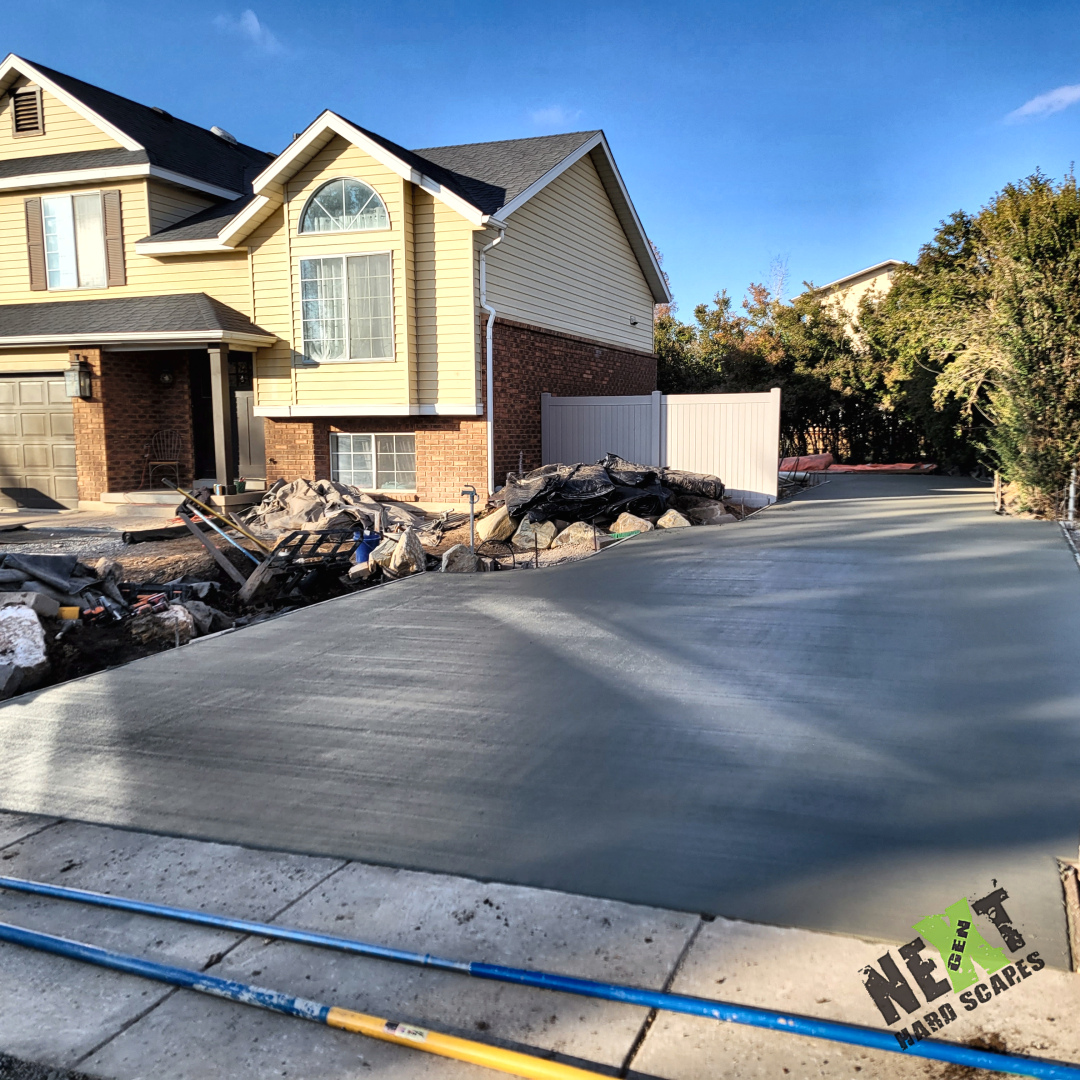 Large driveway slab poured and finished to a consistent texture and elevation, with debris staged along the property edge during cleanup.