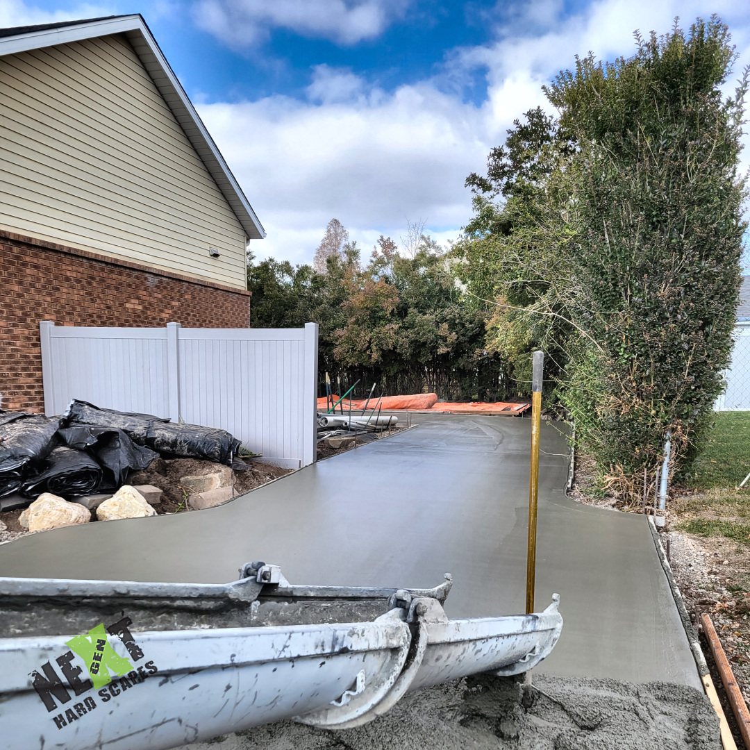 Concrete placement in progress from the chute, pouring continuously toward the backyard with forms and string-line alignment visible.