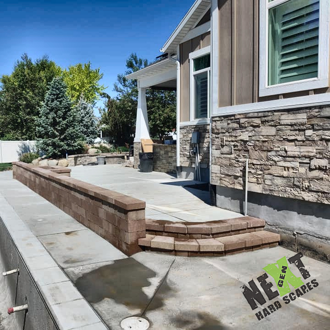 Curved steps connect the raised patio to the pool deck and the long run of wall shows level courses and tight cap joints along the house.