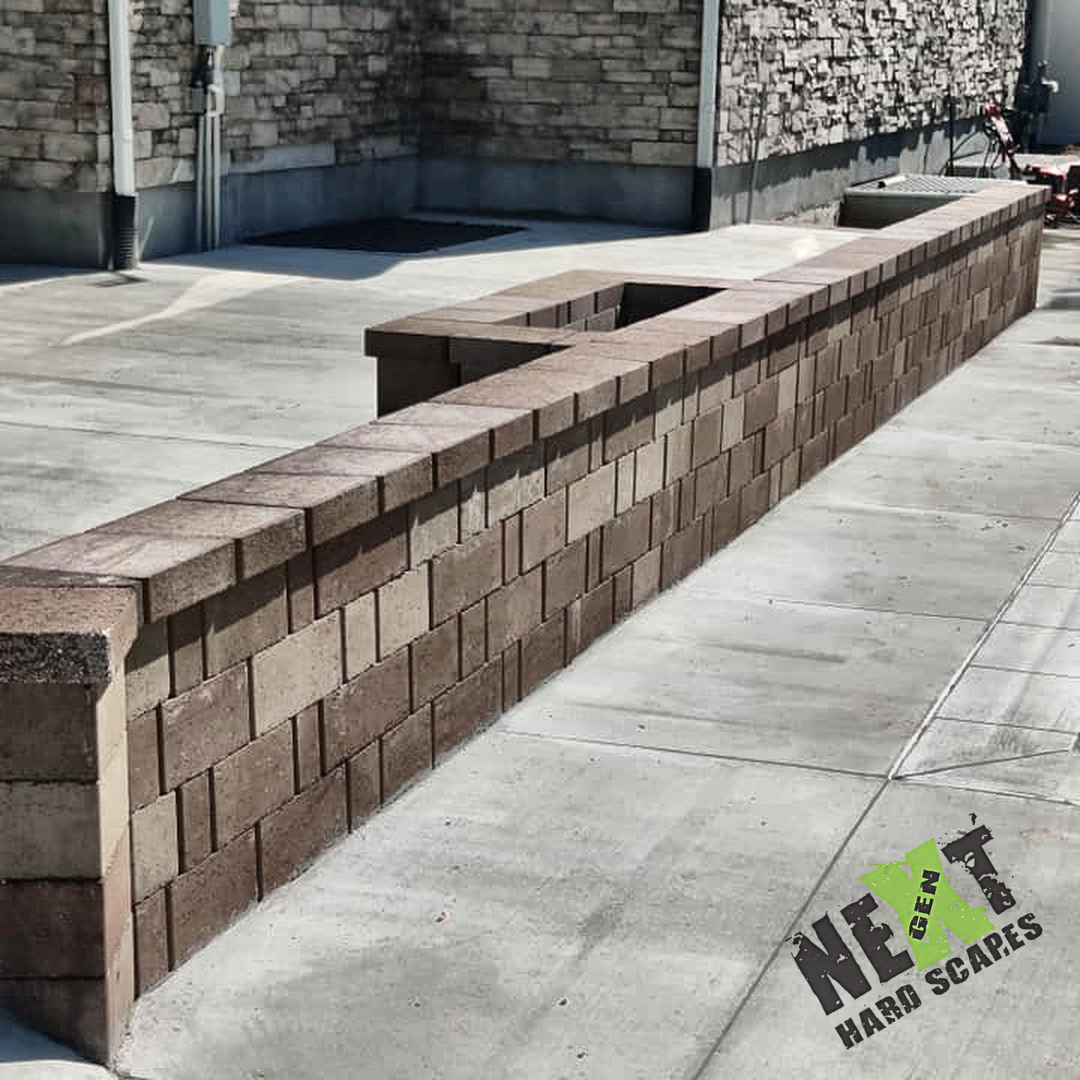 Long straight retaining wall with an integrated seat/planter opening at the corner, blocks stacked with uniform joints and level caps.