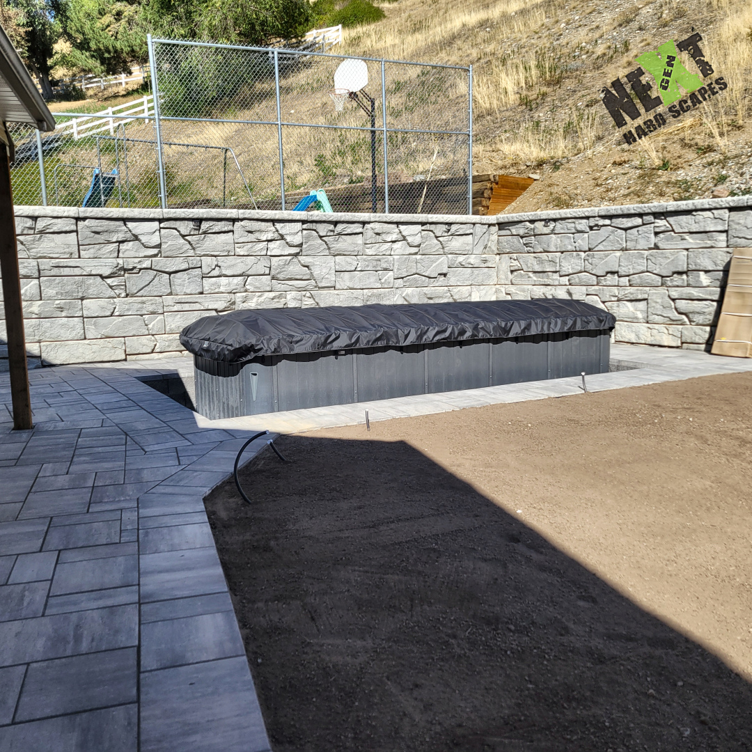 The swim spa is set into its recessed location, with pavers providing solid access along one side. The finished walls keep the spa area defined within the backyard layout. The swim spa is set into its recessed location, with pavers providing solid access along one side. The finished walls keep the spa area defined within the backyard layout.