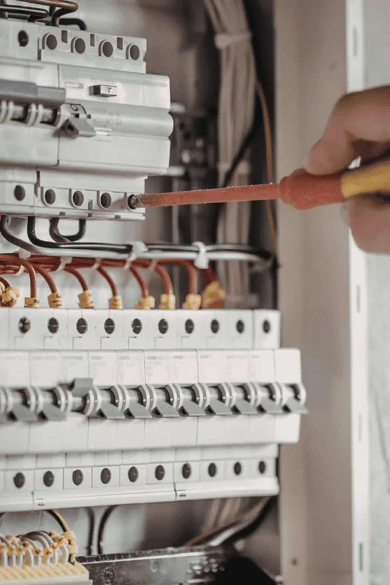 Experienced local electrician using a multimeter tool to test and safely repair a faulty electrical panel in Georgia.