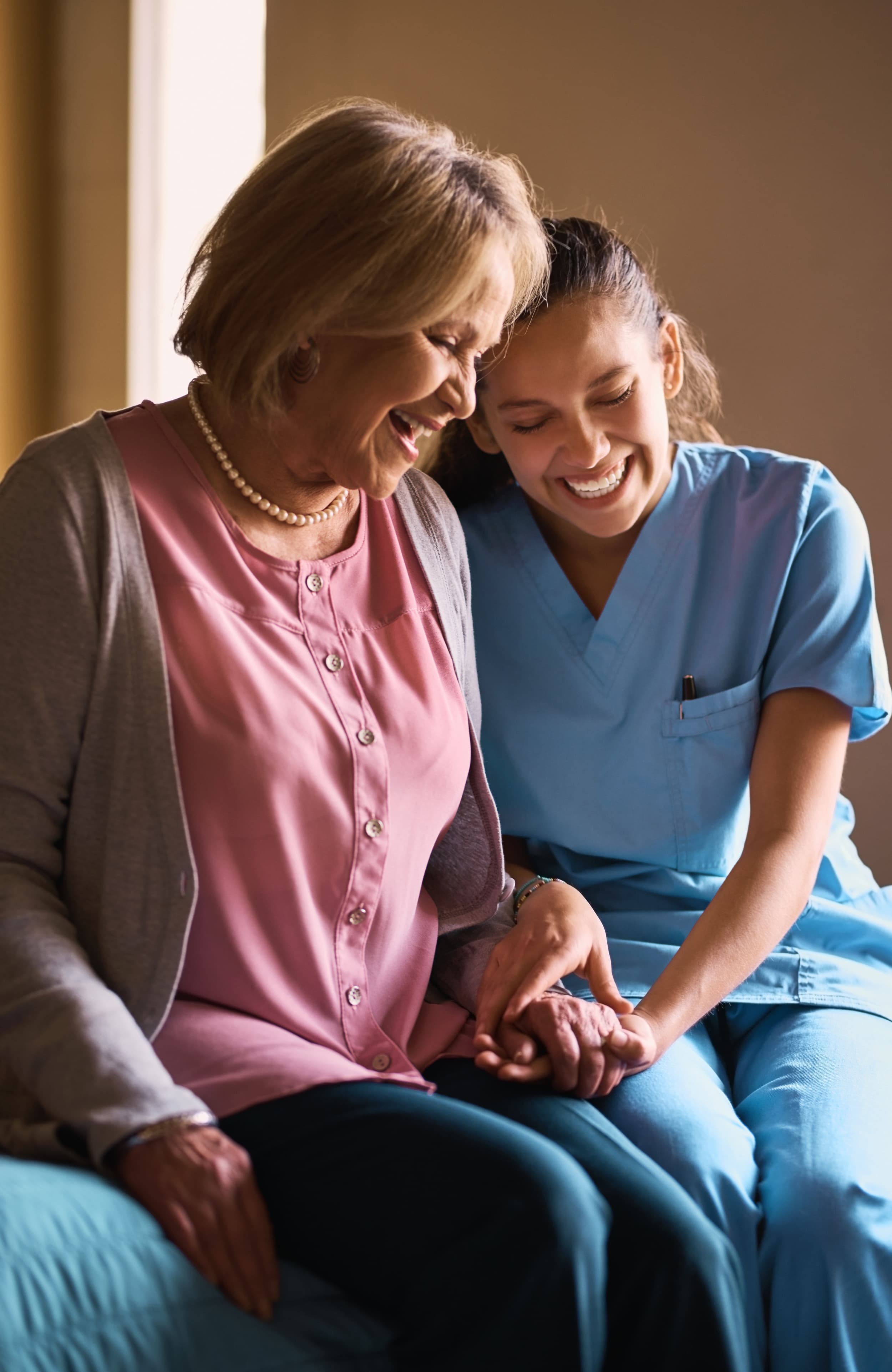 Nurse holding hands with a senior woman, providing compassionate support, healthcare advice, and emotional care in a home setting.