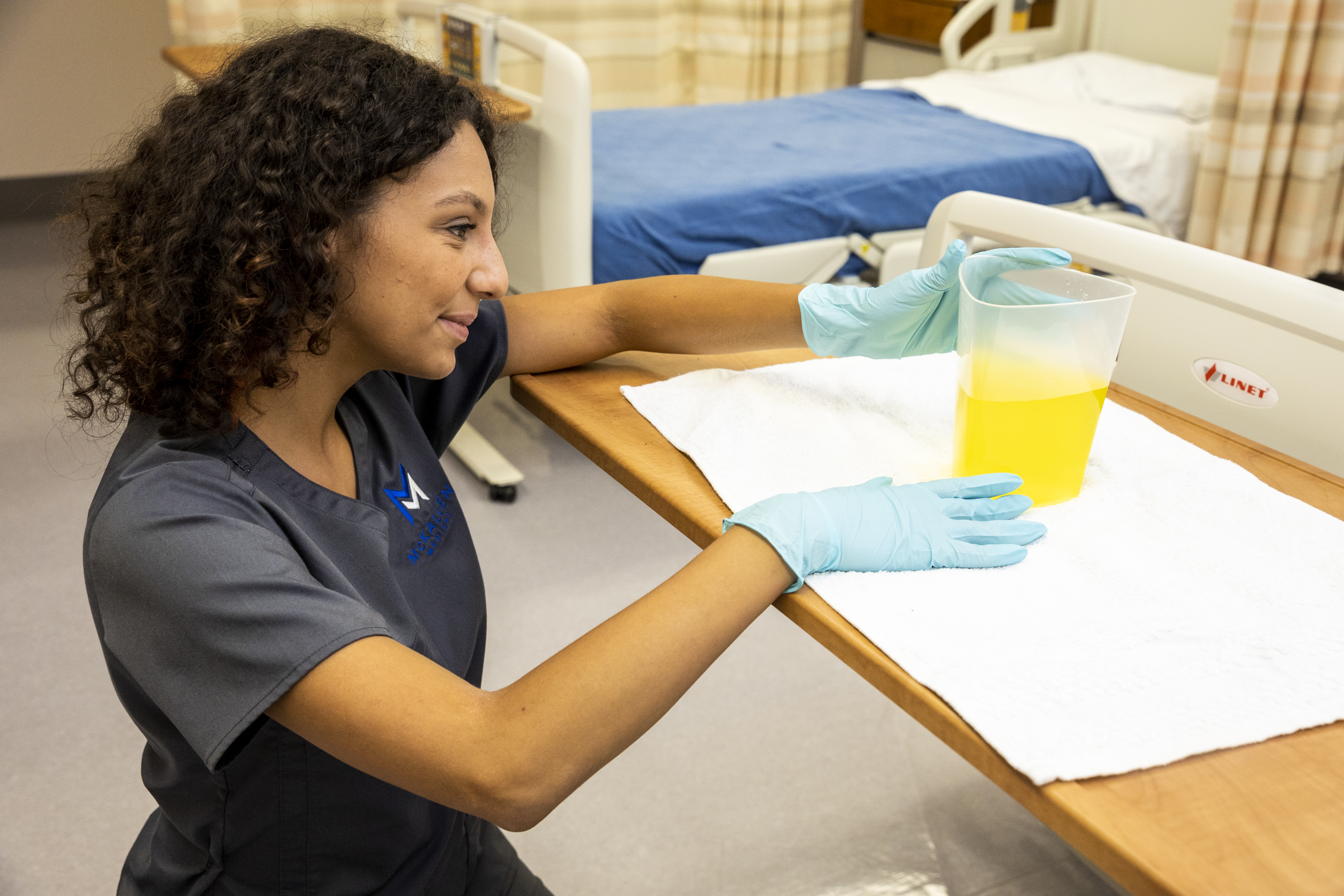 CNA student measuring intake and output fluids in lab
